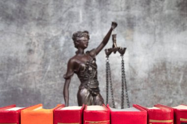 Hukuk konsepti - açık hukuk kitabı, yargıç tokmağı, teraziler, mahkeme salonundaki ya da kolluk kuvvetlerindeki heykel. Tahta masa, gri beton arka plan..