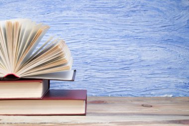 Açık bir kitap, mavi arka planda kitaplar. Okula dönelim. Eğitim. Metin için alanı kopyala