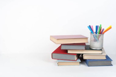 Açık bir kitap, ahşap masa üzerinde ciltli renkli kitaplar, beyaz arka plan. Okula dönelim. Uzayı metin için kopyala. Eğitim sektörü kavramı