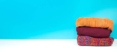 Yünlü yün kazaklar. Kış örgüsü, mavi arka planda sonbahar kıyafetleri, kazaklar, örgü giysiler, yazı için yer. Pankart.