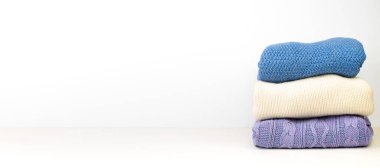 Yünlü yün kazaklar. Bir demet örülmüş kış, arka planda sonbahar kıyafetleri, süveterler, örgü giysiler, yazı için yer. Pankart