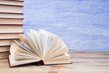 Açık bir kitap, mavi arka planda kitaplar. Okula dönelim. Eğitim. Metin için alanı kopyala