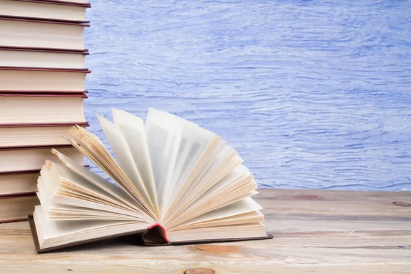 Açık bir kitap, mavi arka planda kitaplar. Okula dönelim. Eğitim. Metin için alanı kopyala