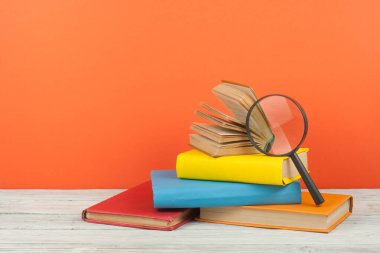 Açık kitap, ahşap masa üzerinde renkli ciltli kitap. Büyüteç'i. Okula dönüş. Metin için yer kopyalayın. Eğitim iş kavramı