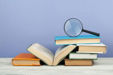 Açık kitap, ahşap masa üzerinde renkli ciltli kitap. Büyüteç'i. Okula dönüş. Metin için yer kopyalayın. Eğitim iş kavramı