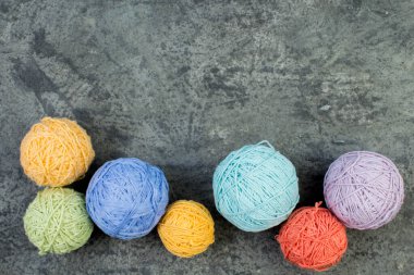 Gri beton arka planda renkli iplik. Örgü örmek için yün derileri. Ahşap arka planda el yapımı örgü örmek için farklı renkte yün toplar ve reklam için kopya alanı