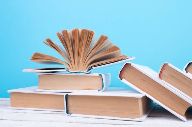 Açık kitaplar, ahşap masada ciltli renkli kitaplar. mavi arka plan. Okula dönelim. Uzayı metin için kopyala. Eğitim sektörü kavramı