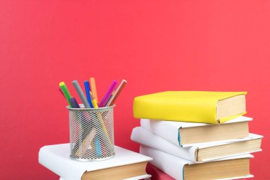 Kitaplar istifleniyor. Kitaplar ahşap masada ve kırmızı arka planda. Okula dönelim. Reklam metni için alanı kopyala