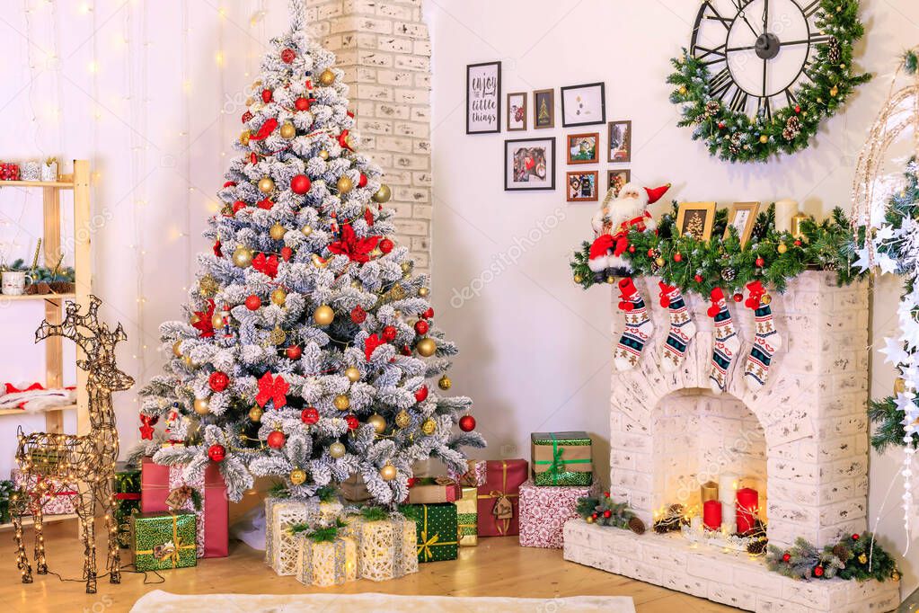 Christmas decor of the living room . the decoration of the room. Christmas snow-covered fir tree with toys. gift boxes under the tree. cozy fireplace in the room. Greeting card. Interior. Article about Christmas . Garland