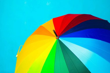 Mavi arka planda renkli şemsiye. Parlak şemsiye. Uzayı kopyala Yağmurdan korunma hakkında makale.