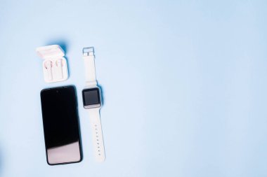 Saatin düzeni ve telefonun mavi arkaplandaki hali. Cihazlar ve elektronik aletler. Modern aletler. Telefon kulaklığı saat. İş için. Öğrenci. Kablosuz kulaklık. Adım sayacıyla izle. Boşluğu kopyala