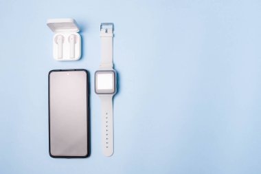 Saatin düzeni ve telefonun mavi arkaplandaki hali. Cihazlar ve elektronik aletler. Modern aletler. Telefon kulaklığı saat. İş için. Öğrenci. Kablosuz kulaklık. Adım sayacıyla izle. Boşluğu kopyala