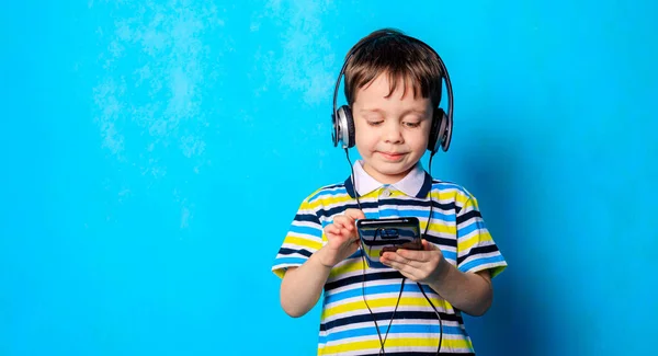 Chłopak Słucha Muzyki Słuchawkami Telefonie Emocjonalny Chłopiec Niebieskie Tło Chłopiec — Zdjęcie stockowe