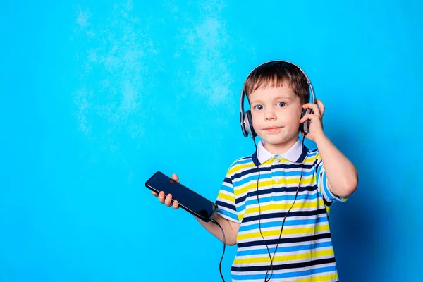 Chłopak Słucha Muzyki Słuchawkami Telefonie Emocjonalny Chłopiec Niebieskie Tło Chłopiec — Zdjęcie stockowe