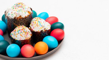 Renkli boyalı yumurta ve beyaz arka planda bir tabakta Paskalya pastası. Paskalya. Dini bayram. Metin için yer.