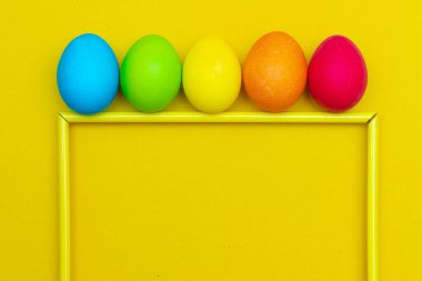 Sarı arka planda boyalı yumurtalar. Sarı arka planda tavuk yumurtası. Metin için yer aç. Tavuk yumurtaları renklidir. Paskalya. Ortodoks bayramı. Paskalya hakkında bir makale. Yumurtaların faydaları ve zararları hakkında bir makale. Uzayı kopyala Sarı arkaplan