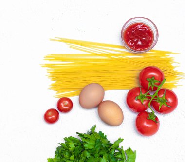 Beyaz arka planda spagetti ve domates. Spagetti pişirmek için gerekli malzemeler. Beyaz arka plan. Uzun makarna. Domates. Taze sebzeler. İtalyan yemeği. Hazırlık. Boşluğu kopyala