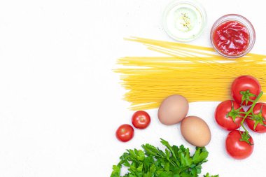 Beyaz arka planda spagetti ve domates. Spagetti pişirmek için gerekli malzemeler. Beyaz arka plan. Uzun makarna. Domates. Taze sebzeler. İtalyan yemeği. Hazırlık. Boşluğu kopyala