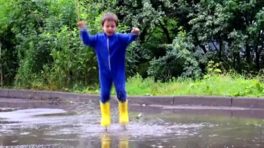 Çocuk bir su birikintisine atladı. Lastik çizmeli bir çocuk. Mutlu bir çocukluk. Yaz. Yaz birikintileri. Yağmurdan sonra taze. Çocuklar eğleniyor..