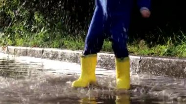 Çocuk bir su birikintisine atladı. Lastik çizmeli bir çocuk. Mutlu bir çocukluk. Yaz. Yaz birikintileri. Yağmurdan sonra taze. Çocuklar eğleniyor..