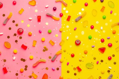 Şekerleme çeşitleri. Sarı-pembe arka planda şekerlemeli düzen. Çiğnenmiş marmelat ve küçük karamel. Parlak bir arka plan. Tatlılar hakkında bir makale.