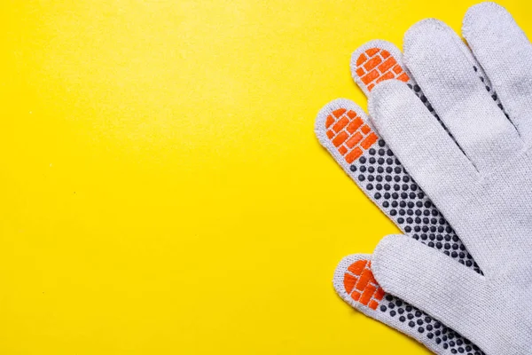 Gardening gloves on a yellow background . Work gloves on a yellow background. Yellow background. An article about dirty work. Hand protection. Copy space