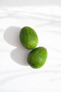 Beyaz arka planda gölgeli bir avokado. Düzgün beslenme. Keto diyeti. Avokadonun faydaları ve zararları hakkında bir makale. Avokado kopyalama alanı
