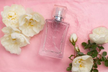 Perfume bottle and flowers on the background and water drops. A bottle of perfume without inscriptions . Smell. Perfume on a pink background. Water drops. Copy space. Article about the choice of perfume