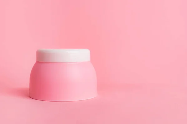 Pink jar with cream on a pink background . Cosmetology. Skin care. Article about the choice of cream. Article about the choice of care cosmetics. Spa treatments. Copy space