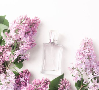 Beyaz arka planda bir şişe parfüm ve leylak. Kadın parfümü. Bahar kokusu. Aromaterapi. Güzel koku. Güzellik ve moda. Parfüm seçimi hakkında bir makale. Mevcut tatlar hakkında bir makale. kopyalama alanı. Leylak dalı. Doğa