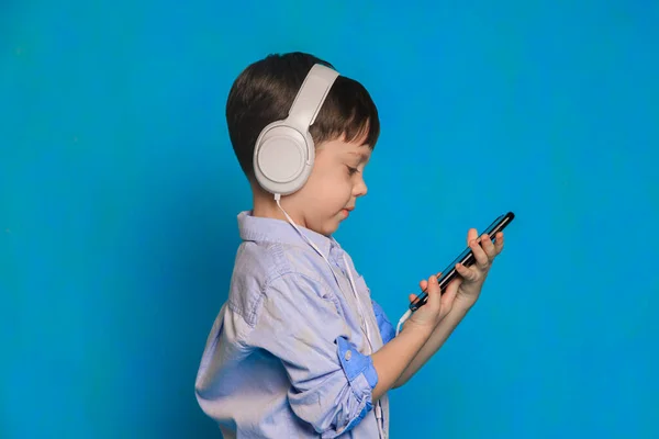 Een Jongen Met Een Koptelefoon Een Blauwe Achtergrond Koptelefoon Voor Rechtenvrije Stockafbeeldingen