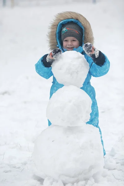 Familie beeldhouwt sneeuwpop — Stockfoto