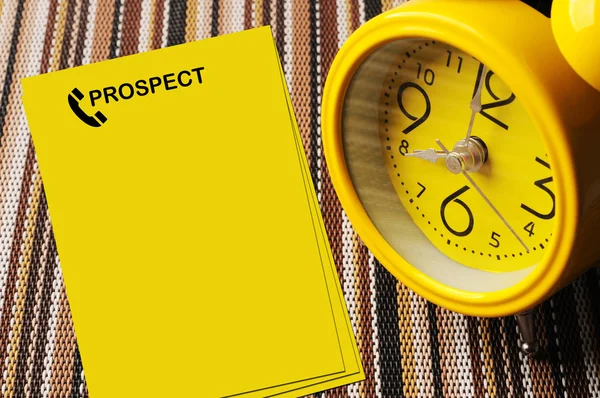 Yellow prospect notes beside close up retro alarm clock on color — Stock Photo, Image