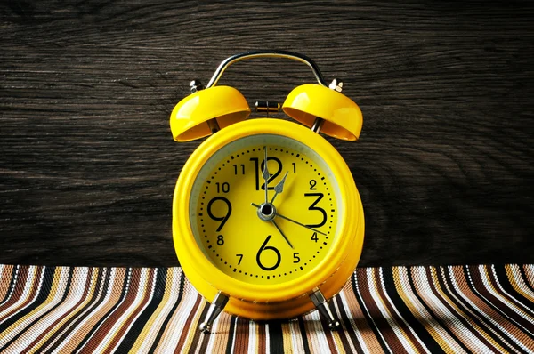 Жовтий ретро будильник на кольоровому килимку показує горизонтальну 1 годину — стокове фото