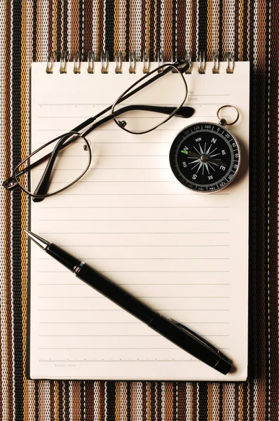 Spectacles, compass and pen on the notepad on the color mat — Stock Photo, Image