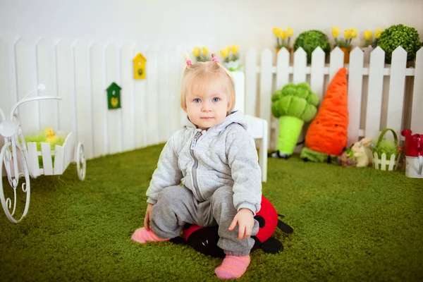 Stüdyodaki yapay çimlerin üzerinde tatlı bir kız bebek.