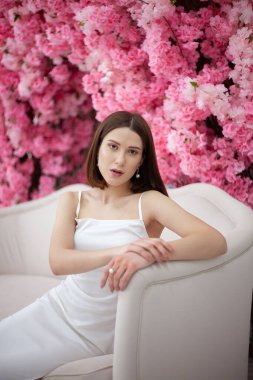 Bahar çiçeklerinin arka planında beyaz elbiseli genç kız.