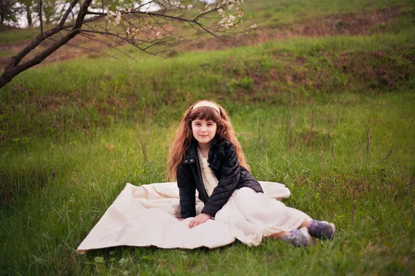 草や花を背景に晴れた春の日に休んでいる女の子 — ストック写真