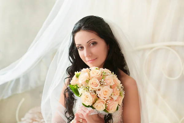 Schöne Braut sitzt mit einem Strauß — Stockfoto