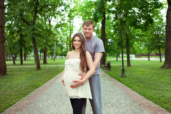 Pregnant woman with her husband in the park — Stock Photo, Image