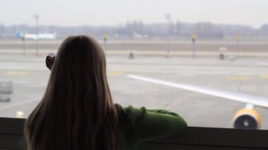 Bekleme odasındaki kız uçağın kalkışını izliyor..
