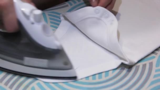 Female hand ironing baby clothes close-up. — Stock Video