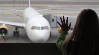 Kız havaalanı penceresinden uçağa baktı..