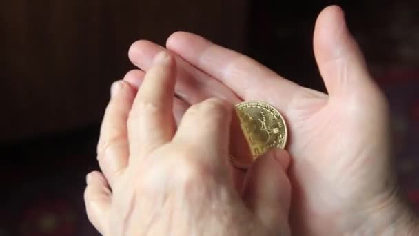 Tangan wanita dari seorang wanita tua memegang bitcoin close-up — Stok Video