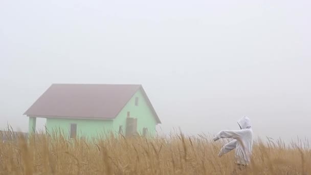 Et muntert spøkelse i tåken i en balaklava nær et forlatt hus – stockvideo