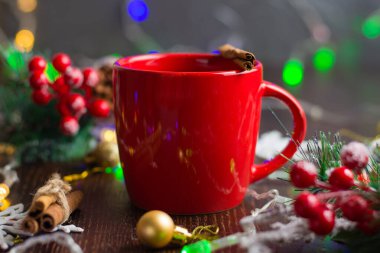 Lezzetli sıcak şarap, alkollü sıcak içecek ve kırmızı bardaklarda tarçın. Yeni yıl tatili için bekleme kavramı. Arka planda Noel çelengi ve bokeh.