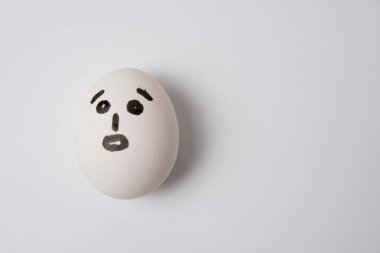 Beyaz arka planda, şaşırmış bir yüzü olan bir yumurta.