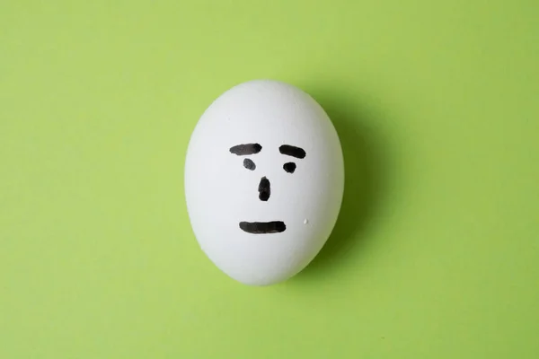 Huevo Con Una Cara Indiferente Sobre Fondo Verde Con Espacio — Foto de Stock
