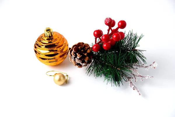Decoración navideña rama de pino, cono de pino y bola amarilla sobre fondo blanco — Foto de Stock