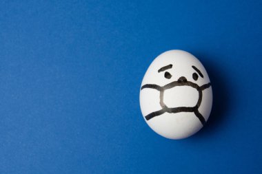 Yüzünde maske olan bir yumurta. Fotokopi alanı olan mavi bir arka plan. İlaç konsepti Covid 19 'u karantinaya al